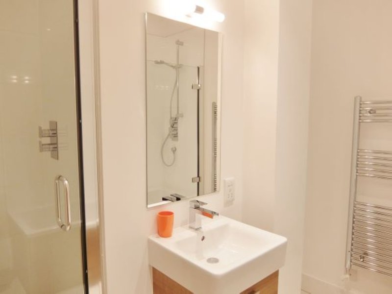 Modern bathroom with white sink, mirror, shower enclosure and heated towel rail