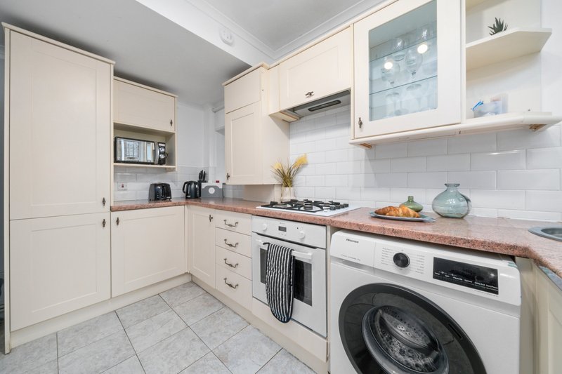 Modern kitchen with cream cabinetry, white subway tiles, gas hob, and integrated washing machine