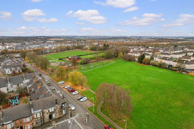Aerial view of residential area with green fields, houses and tree-lined streets