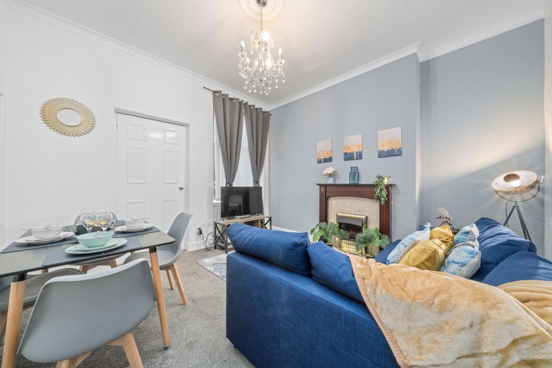 Modern living room with blue sofa, dining table, fireplace, chandelier and wall art