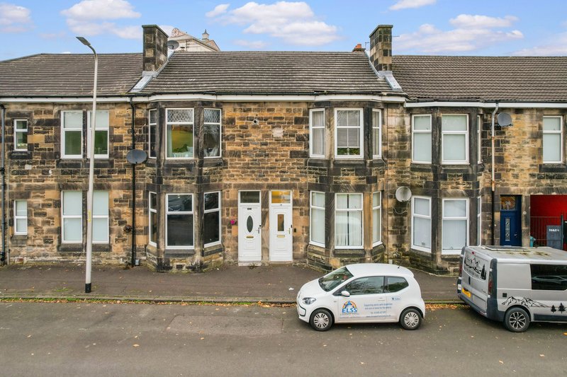 Stone terraced houses with white doors, windows and pitched roof, parked cars on street
