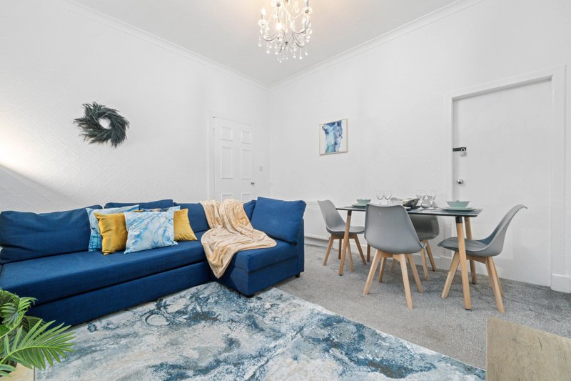 Bright living room with blue sofa, dining table, chairs, and modern decor