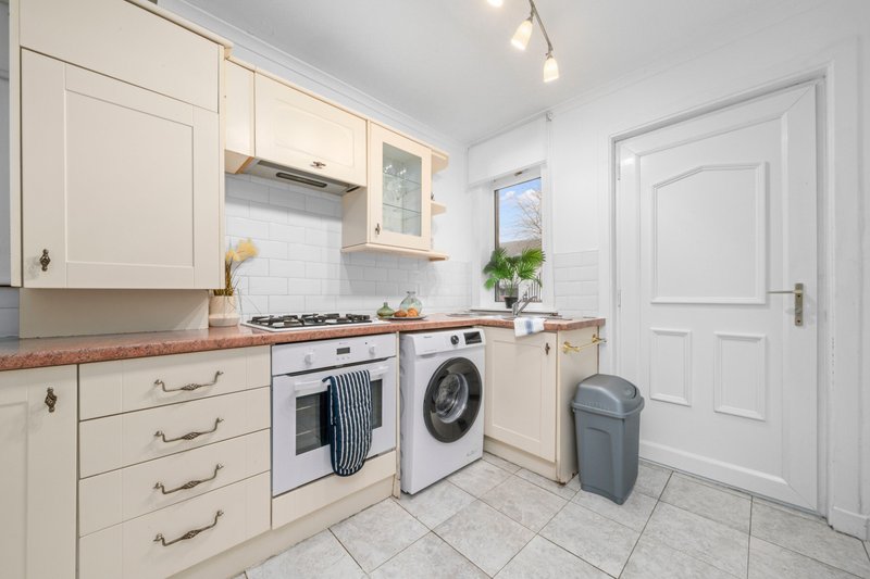 Modern kitchen with cream cabinets, white appliances, tiled floor and natural light