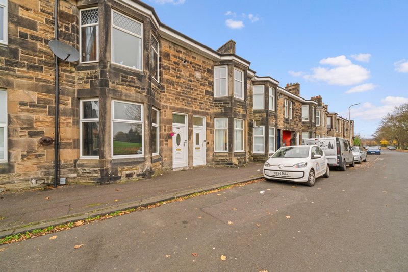 Stone terraced houses with white doors and parked cars on quiet residential street