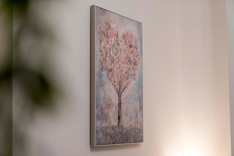 Interior wall with framed painting of pink blossoming tree, soft neutral decor