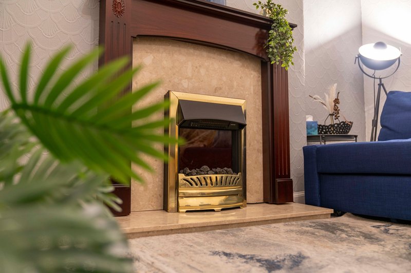Living room with fireplace, blue sofa, potted plant, and floor lamp