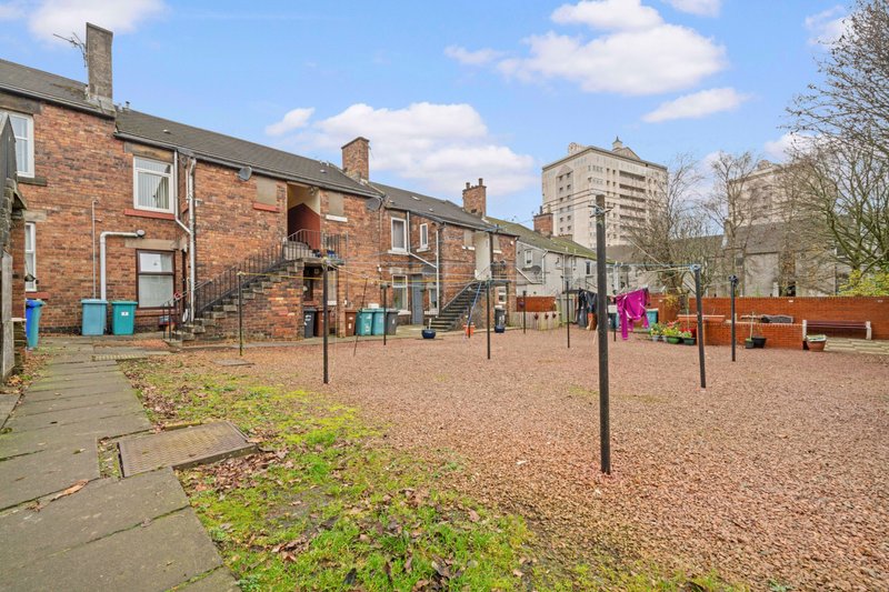 Brick terraced housing with communal courtyard, playground equipment and modern apartment blocks in background
