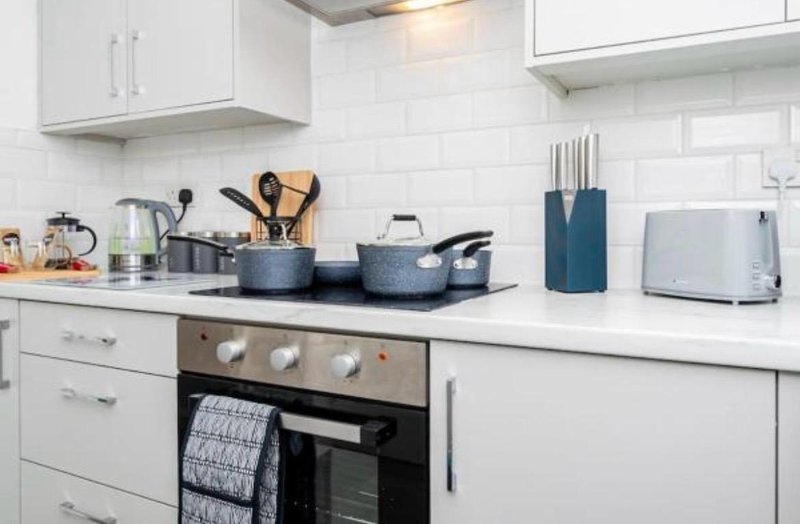 Modern white kitchen with gas stove, cookware, utensils, and appliances on countertop