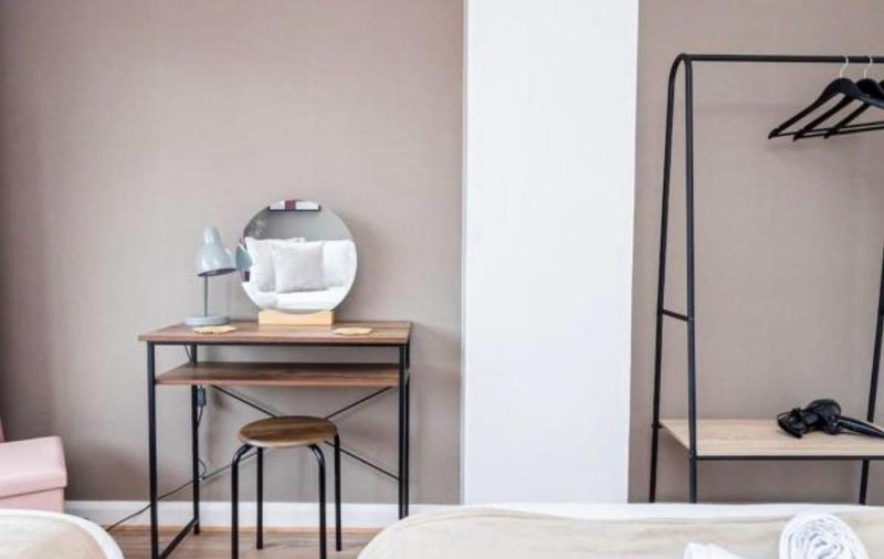 Bedroom with desk, mirror, stool, clothing rack, and neutral decor