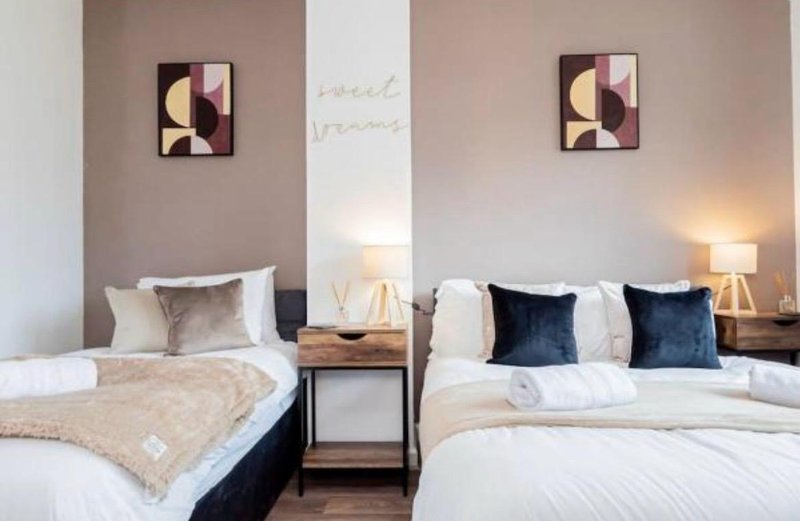 Twin bedroom with two beds, bedside tables, lamps, and abstract wall art