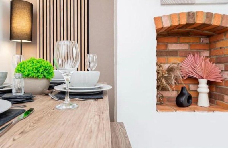 Dining table with place settings, green plant centerpiece, and wall-mounted fireplace decor