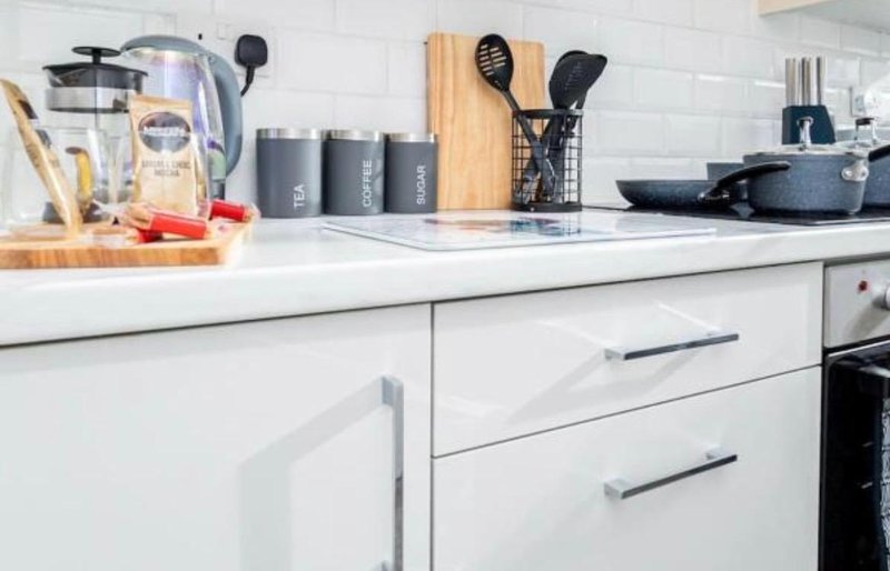 Modern white kitchen with countertop, appliances, utensil holders, and cooking equipment