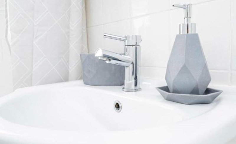 Modern bathroom sink with chrome faucet, gray ceramic accessories and white tile backsplash