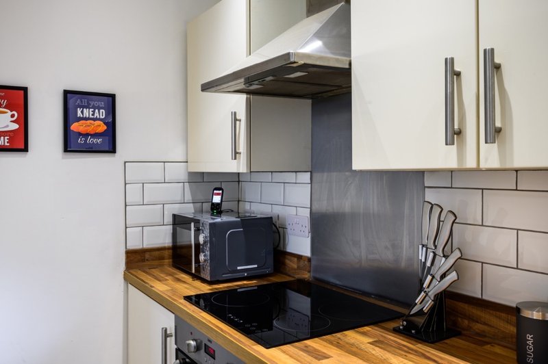 Modern kitchen with white cabinetry, black induction hob, wooden worktop and subway tile splashback