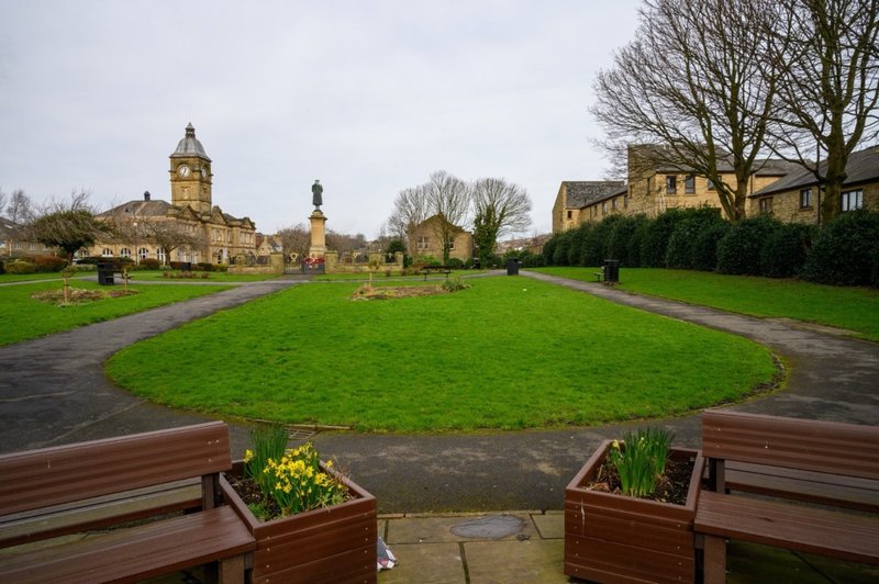 View from bench across green courtyard with historic stone buildings and church tower