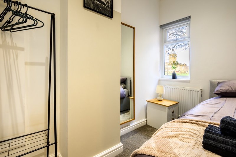 Bedroom with single bed, wardrobe, mirror, window, and bedside lamp