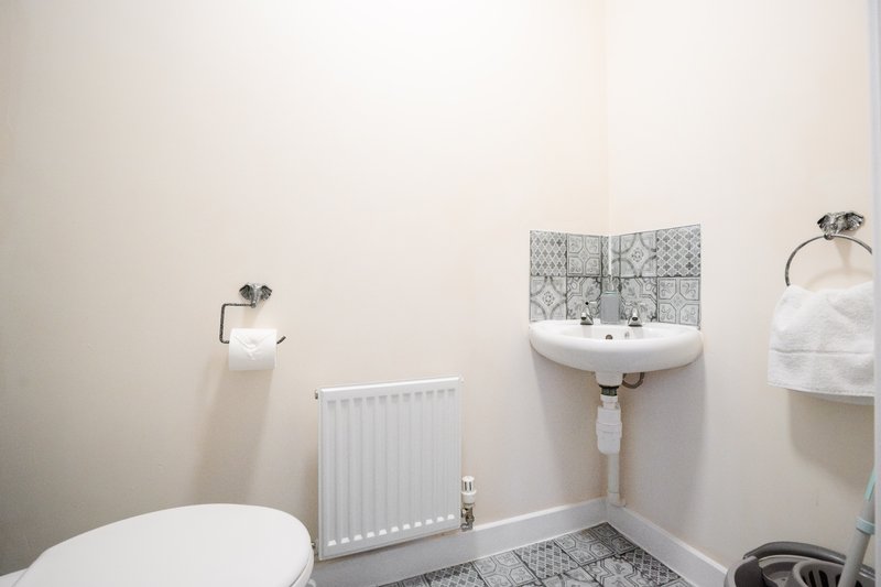 Small bathroom with toilet, pedestal sink, radiator and tiled floor