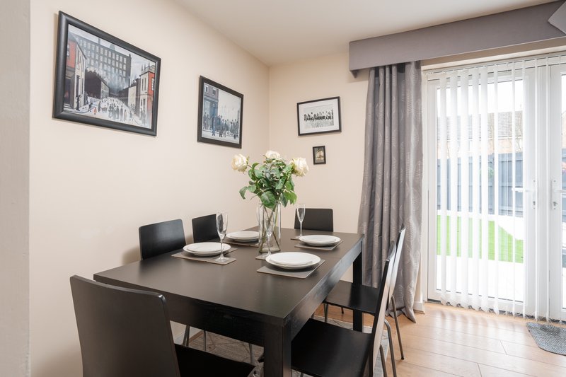 Modern dining room with black table, chairs, fresh flowers, and framed wall art