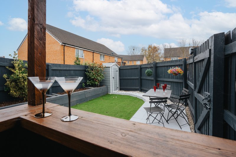 Modern garden with decking, lawn, seating area and brick house backdrop