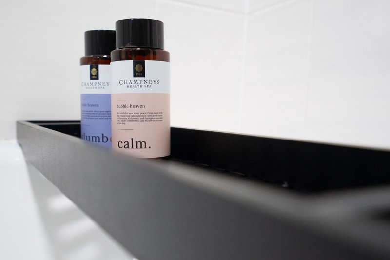 Bathroom shelf with branded toiletry bottles and black tray