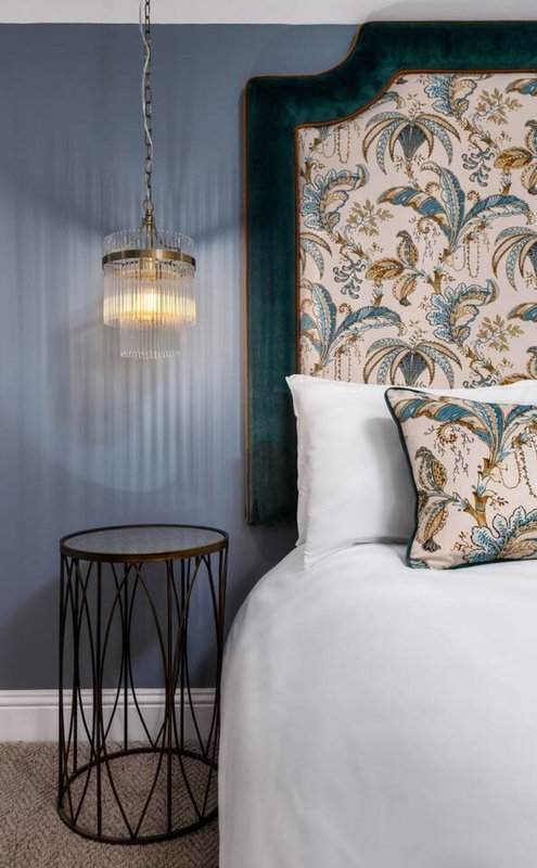 Modern bedroom with upholstered headboard, white bedding, pendant light fixture, and side table