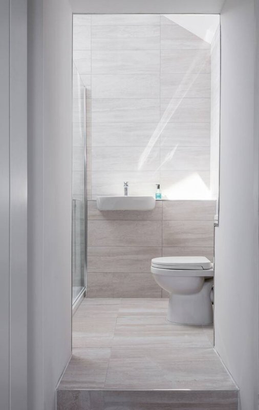 Modern bathroom with toilet, sink, and walk-in shower behind glass door