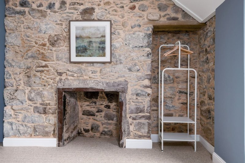 Stone fireplace with framed artwork, white metal towel rack and beige carpet flooring
