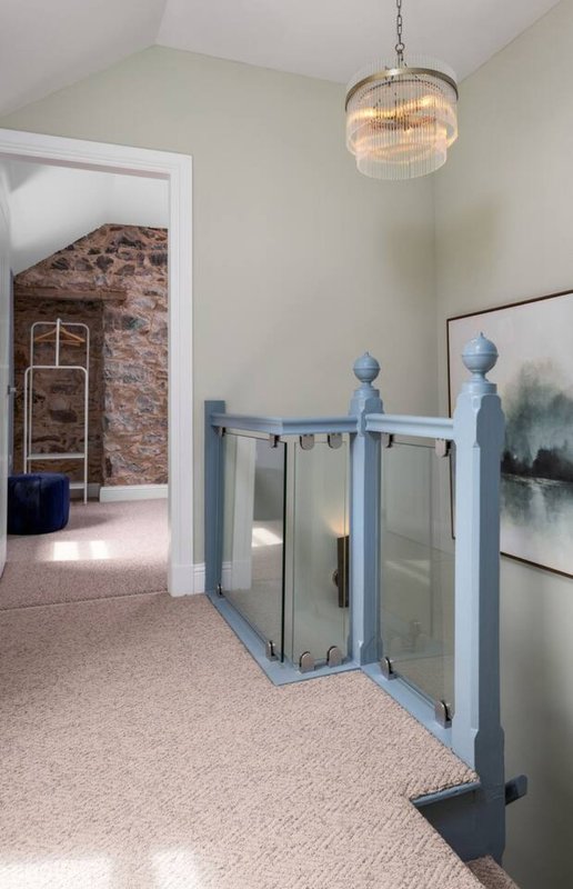 Open-plan upstairs landing with glass stair gate, pendant light, and access to bedroom