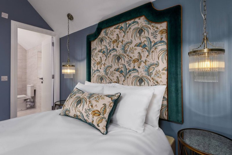 Modern bedroom with double bed, patterned headboard, pendant lights and ensuite bathroom
