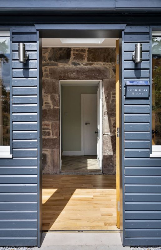 Modern entrance with blue sliding doors, stone archway, wooden flooring and white interior door