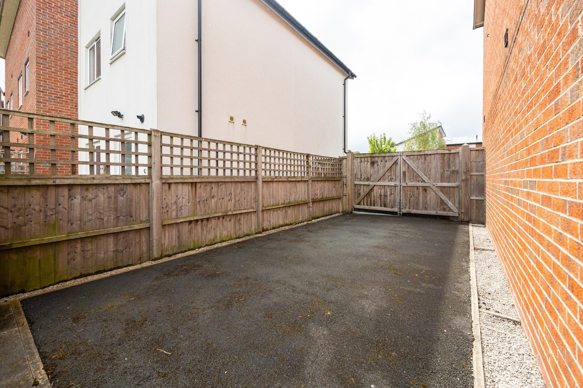 Paved outdoor courtyard with wooden fence gates and brick walls