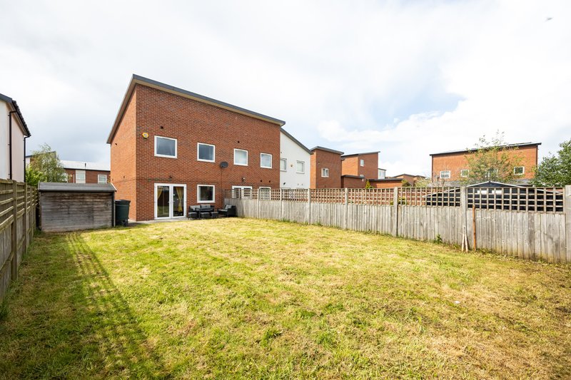 Brick house with white wooden fence and large grassy backyard garden