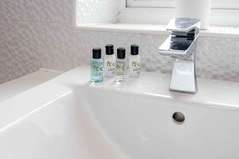 Clean modern bathroom sink with chrome faucet, toiletries, and window above