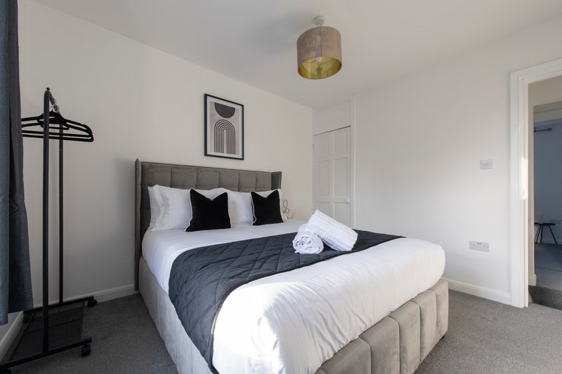 Modern bedroom with double bed, white and navy bedding, pendant light fixture, coat stand