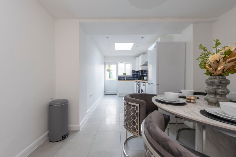 Modern open-plan kitchen and dining area with white cabinetry, dining table set for two, and flowers in vase