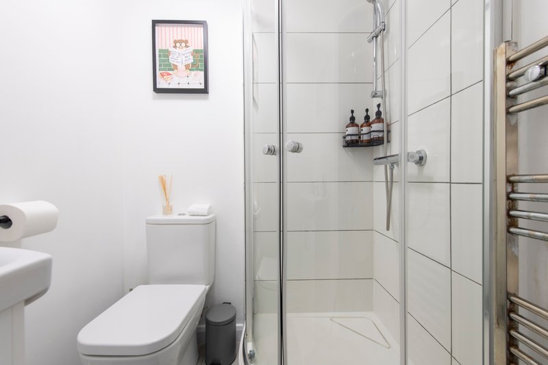Modern bathroom with toilet, white sink, enclosed shower cubicle and heated towel rail