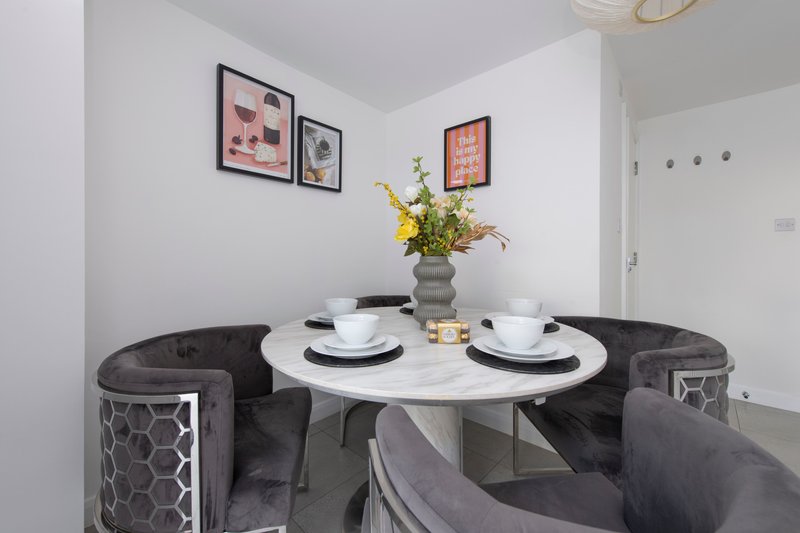 Modern dining nook with round white table, black upholstered seating, place settings and yellow flowers