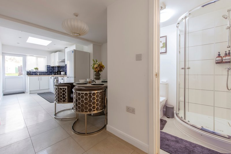 Modern bathroom with shower enclosure, vanity unit with patterned basin, and view into kitchen