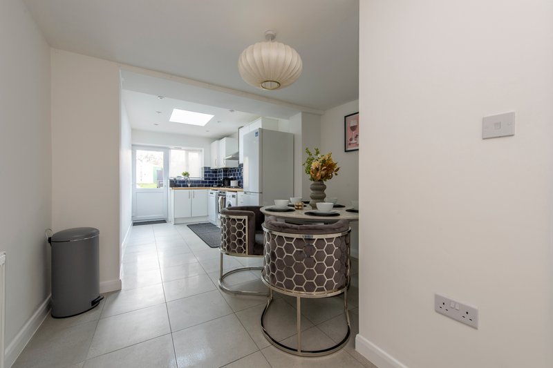 Modern kitchen and dining area with white cabinetry, pendant light, patterned table and chairs