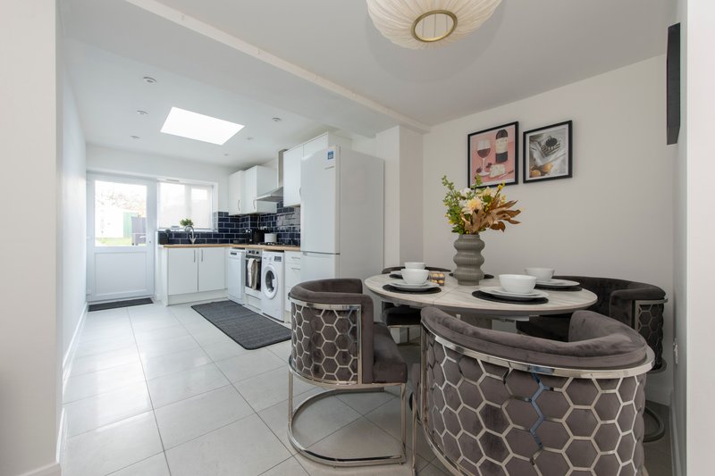 Modern kitchen-diner with white cabinetry, dining table, patterned chairs and wall art