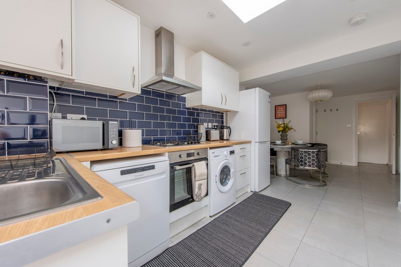 Modern kitchen with white cabinets, blue tile backsplash, wooden countertop and integrated appliances