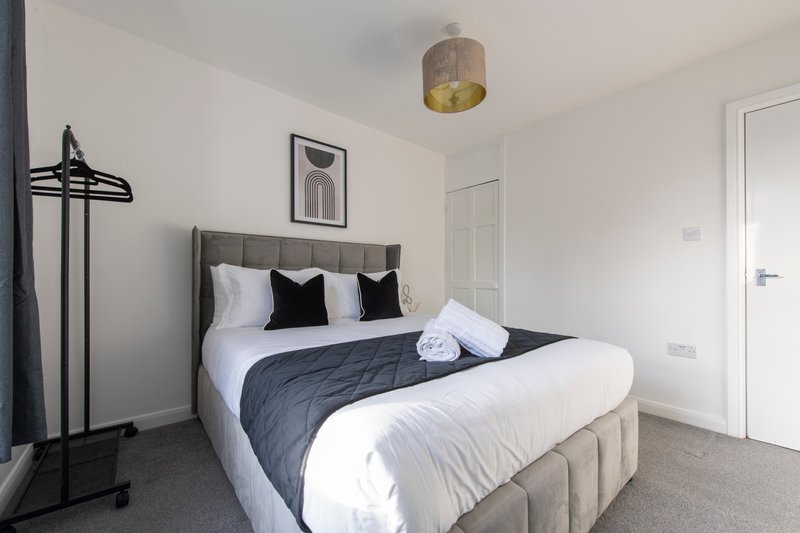 Modern bedroom with double bed, black and white bedding, pendant light fixture, and wall art