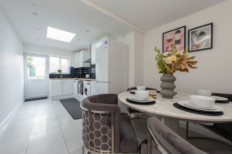Modern kitchen-diner with white cabinetry, dining table set for four, and decorative wall art