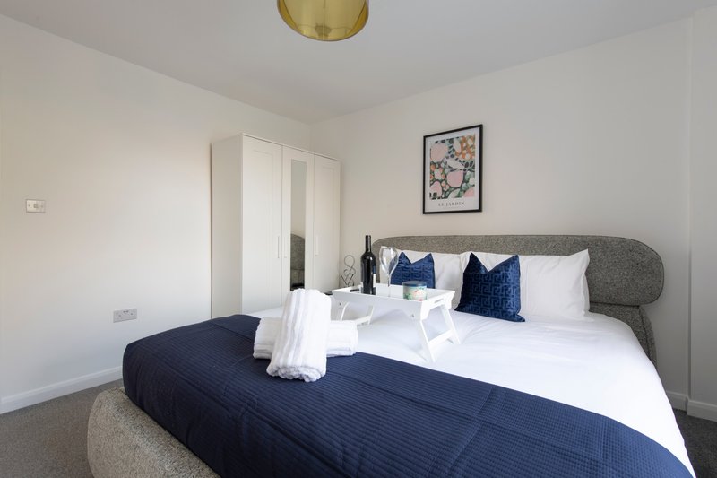 Modern bedroom with double bed, navy bedding, grey headboard and wall art