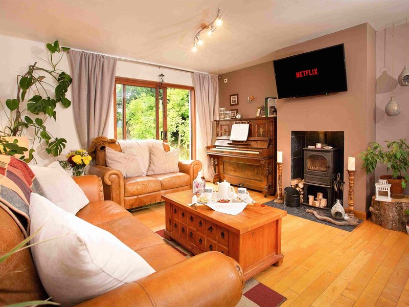 Warm living room with tan leather sofas, wooden coffee table, fireplace, and wall-mounted TV