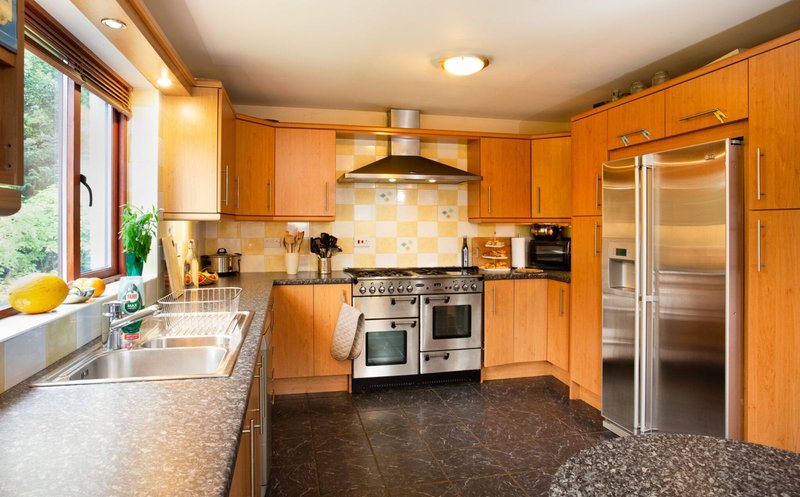 Bright modern kitchen with wooden cabinets, stainless steel appliances and granite counters