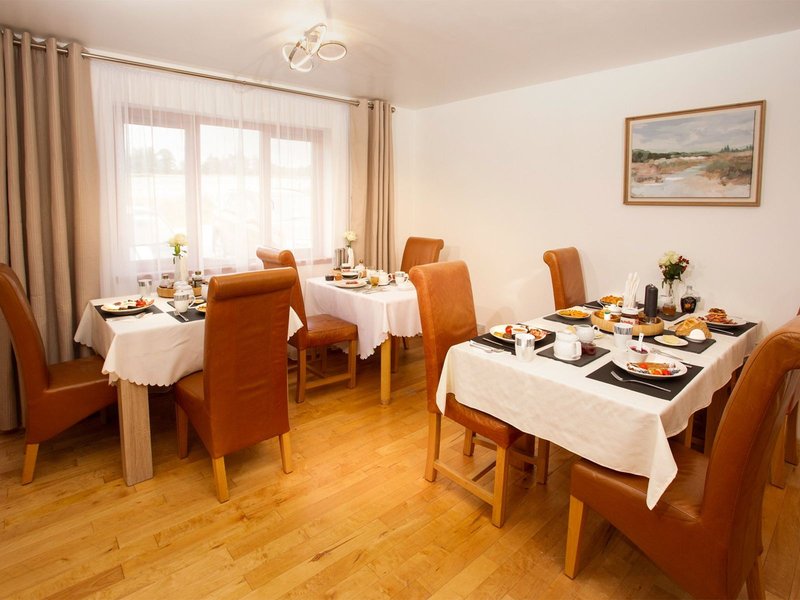 Dining room with wooden tables, orange chairs, white tablecloths and place settings