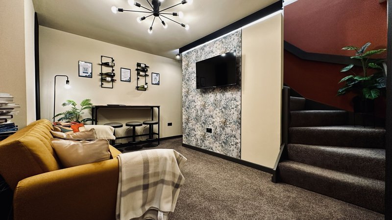 Modern living room with mustard sofa, wall-mounted TV, desk area, and floating shelves