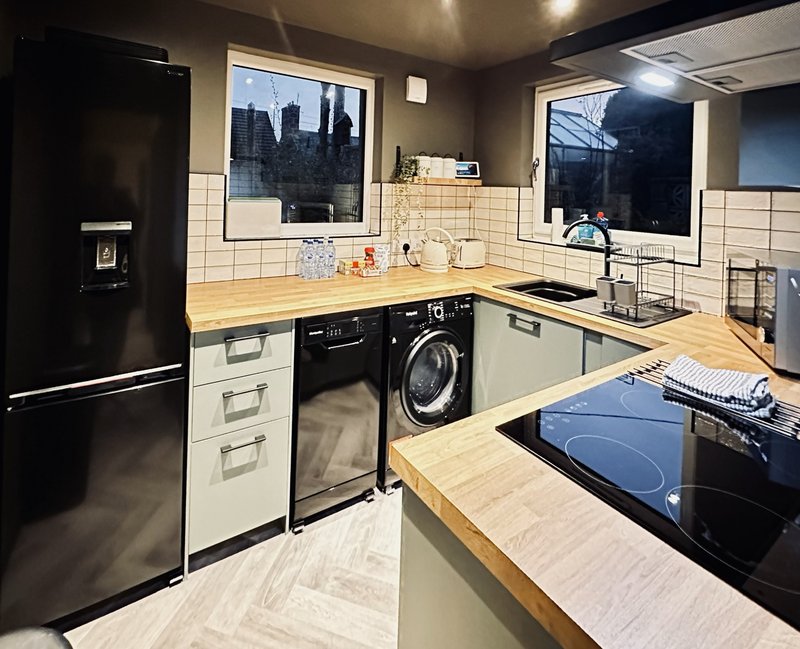 Modern kitchen with black and white cabinetry, wood countertops, stainless steel appliances and city views