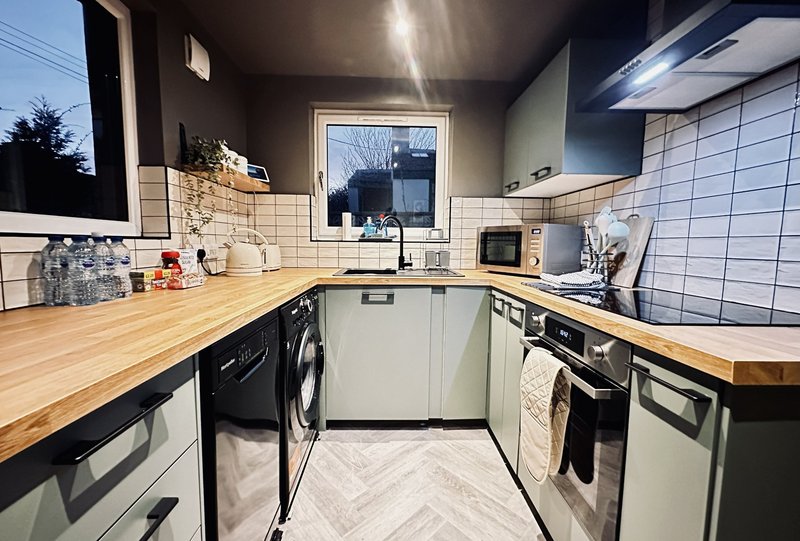 Modern kitchen with white cabinetry, wooden countertops, stainless steel appliances and subway tile backsplash